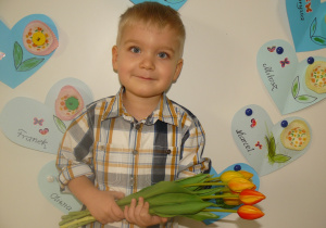 Chłopiec stoi z bukietem kwiatów dla Babci i Dziadka